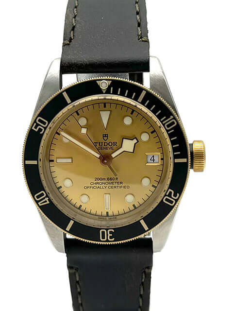 Tudor Black Bay Steel Gold 79733N Uhr mit champagnerfarbenem Zifferblatt, schwarzer Lünette und braunem Lederband.