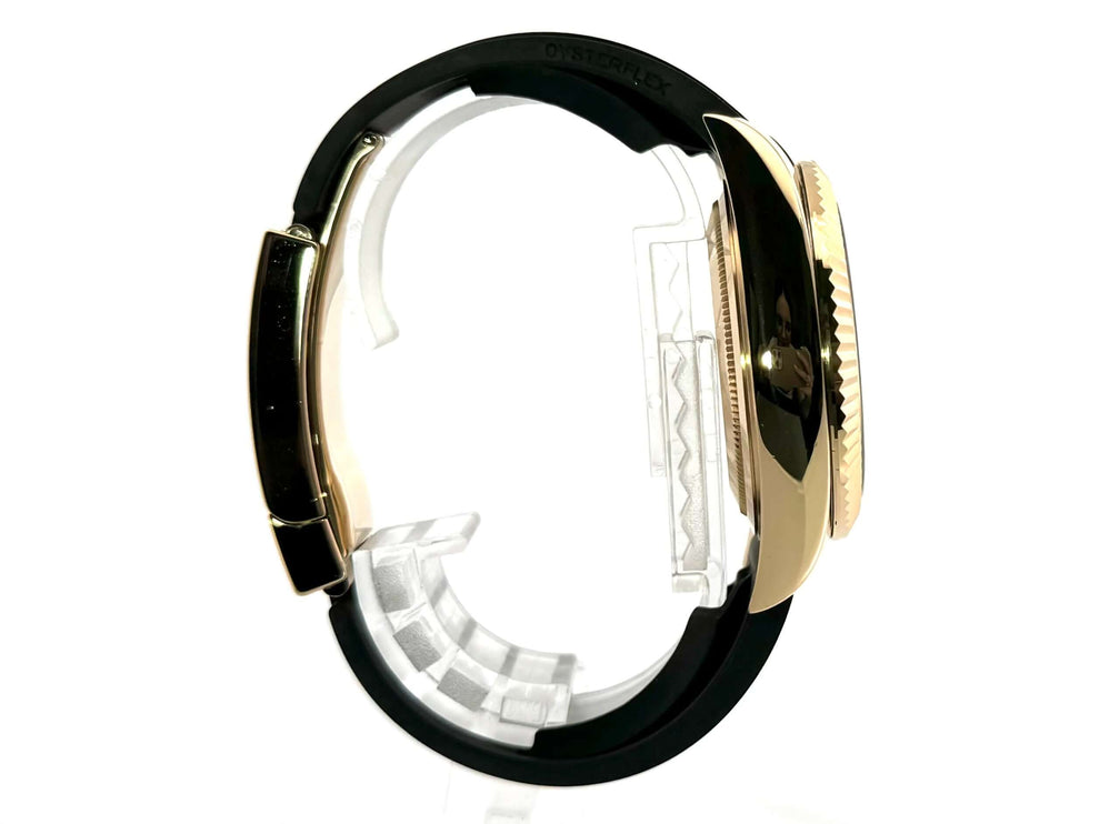 Seitenansicht der Rolex Sky-Dweller Gelbgold 326238 mit schwarzem Oysterflex-Armband und geriffelter Lünette.